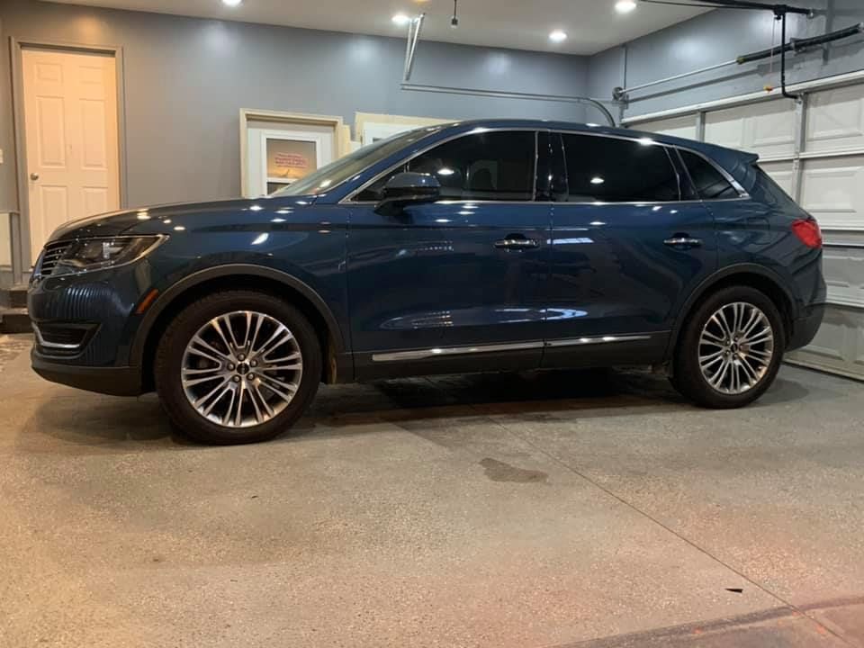 A blue car is parked in a garage next to a garage door.