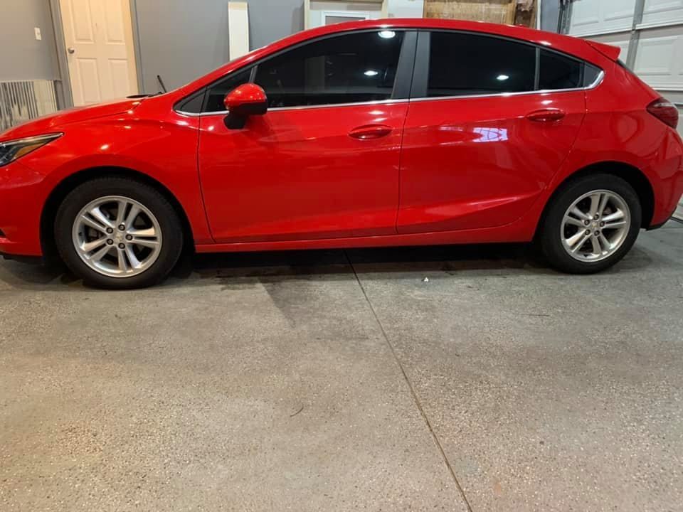 A red car is parked in a garage next to a garage door.