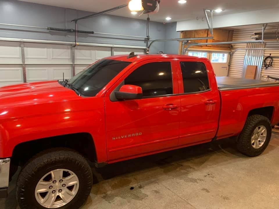 A red truck is parked in a garage under a garage door.