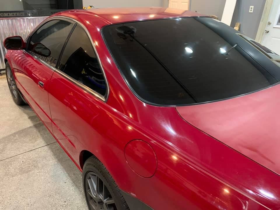 A red car with black windows is parked in a garage.