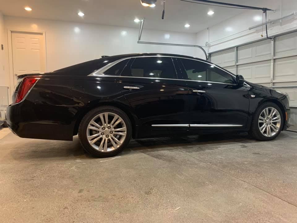 A black car is parked in a garage next to a garage door.