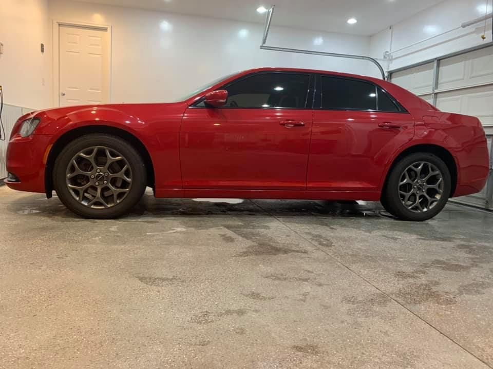 A red car is parked in a garage next to a garage door.