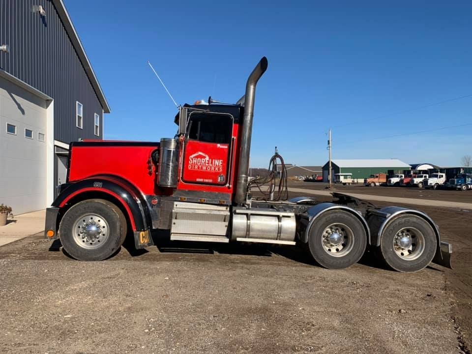 A red semi truck is parked in front of a building.
