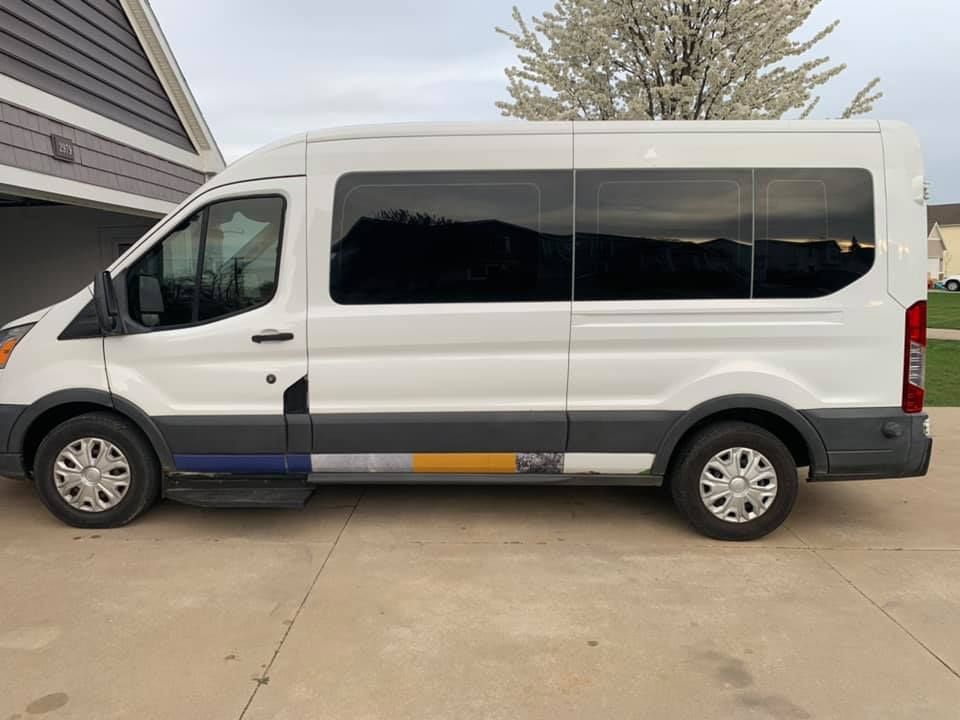 A white van is parked in a driveway next to a house.