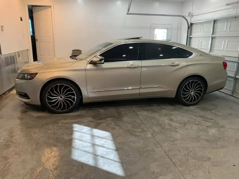 A silver car is parked in a garage next to a garage door.
