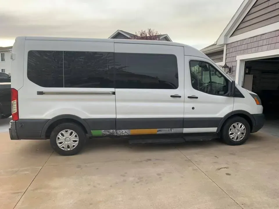 A white van is parked in a driveway next to a garage.
