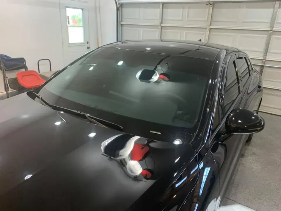 A black car is parked in a garage next to a garage door.