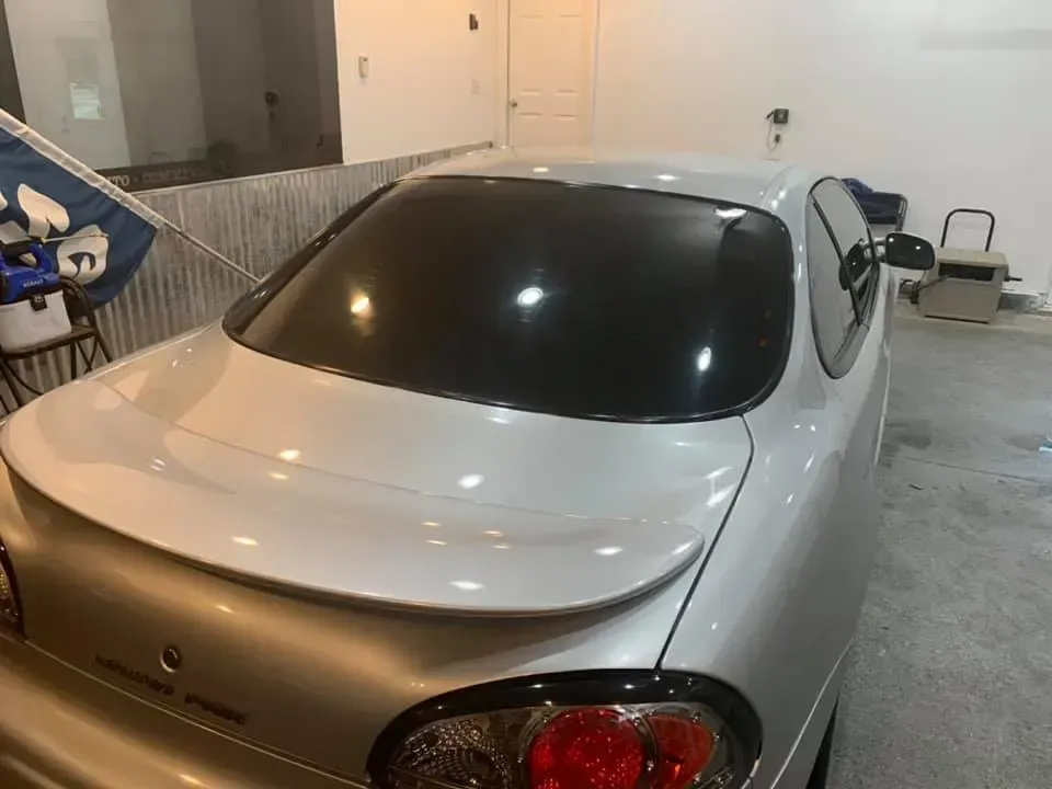 A silver car is parked in a garage next to a flag.