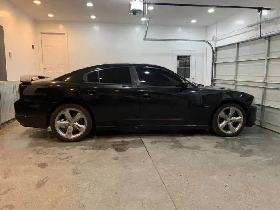 A black car is parked in a garage next to a garage door.