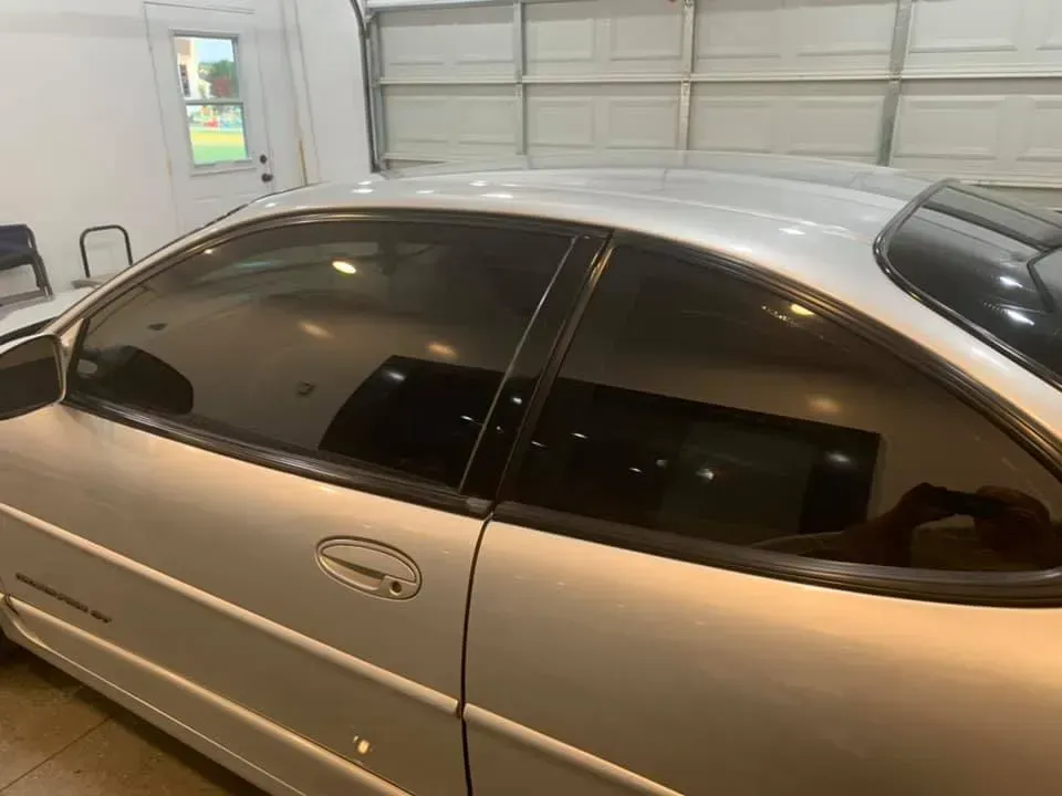 A silver car is parked in a garage next to a garage door.