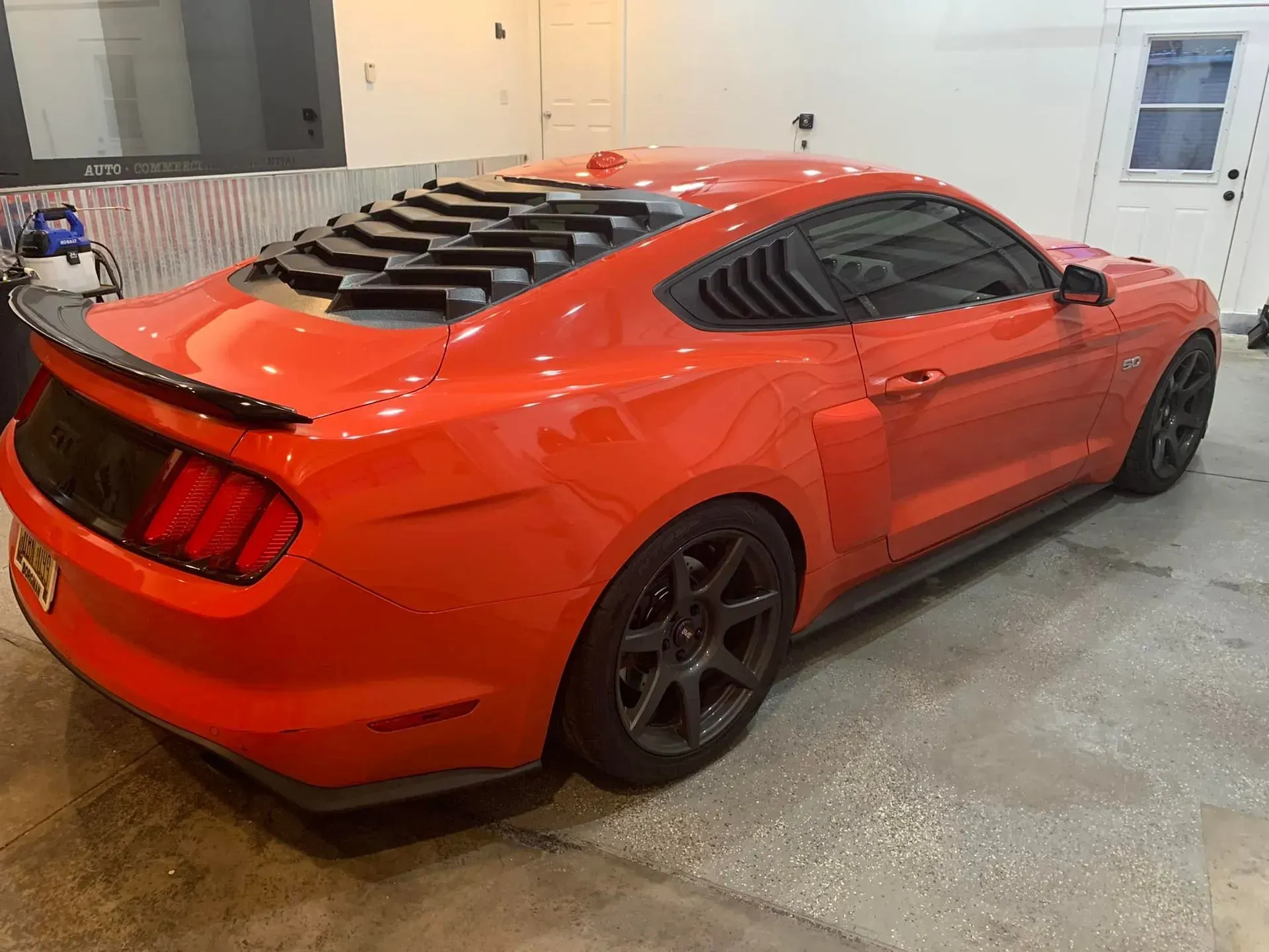 A red ford mustang is parked in a garage.