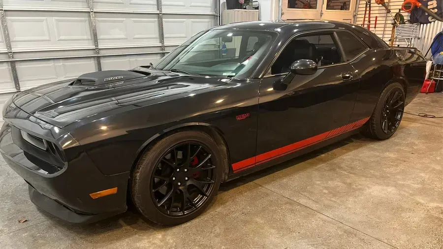 A black dodge challenger is parked in a garage.