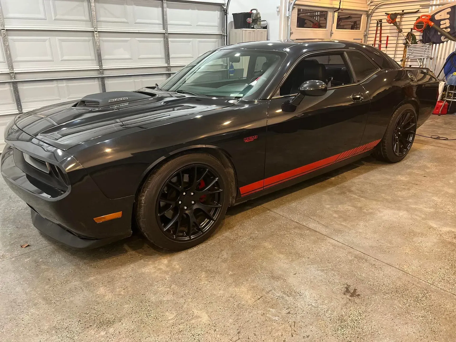 A black dodge challenger is parked in a garage.