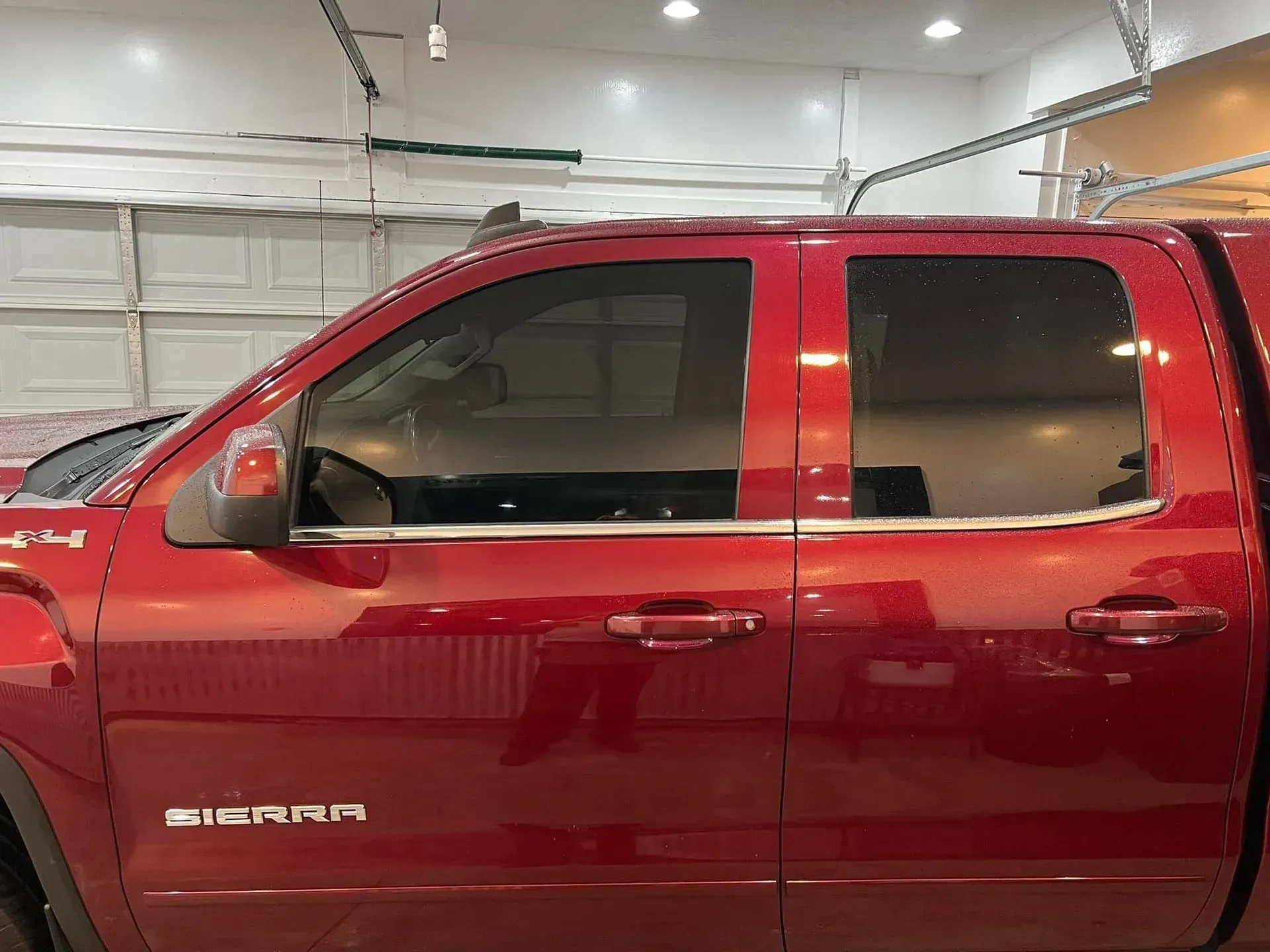 A red truck is parked in a garage with its doors open.