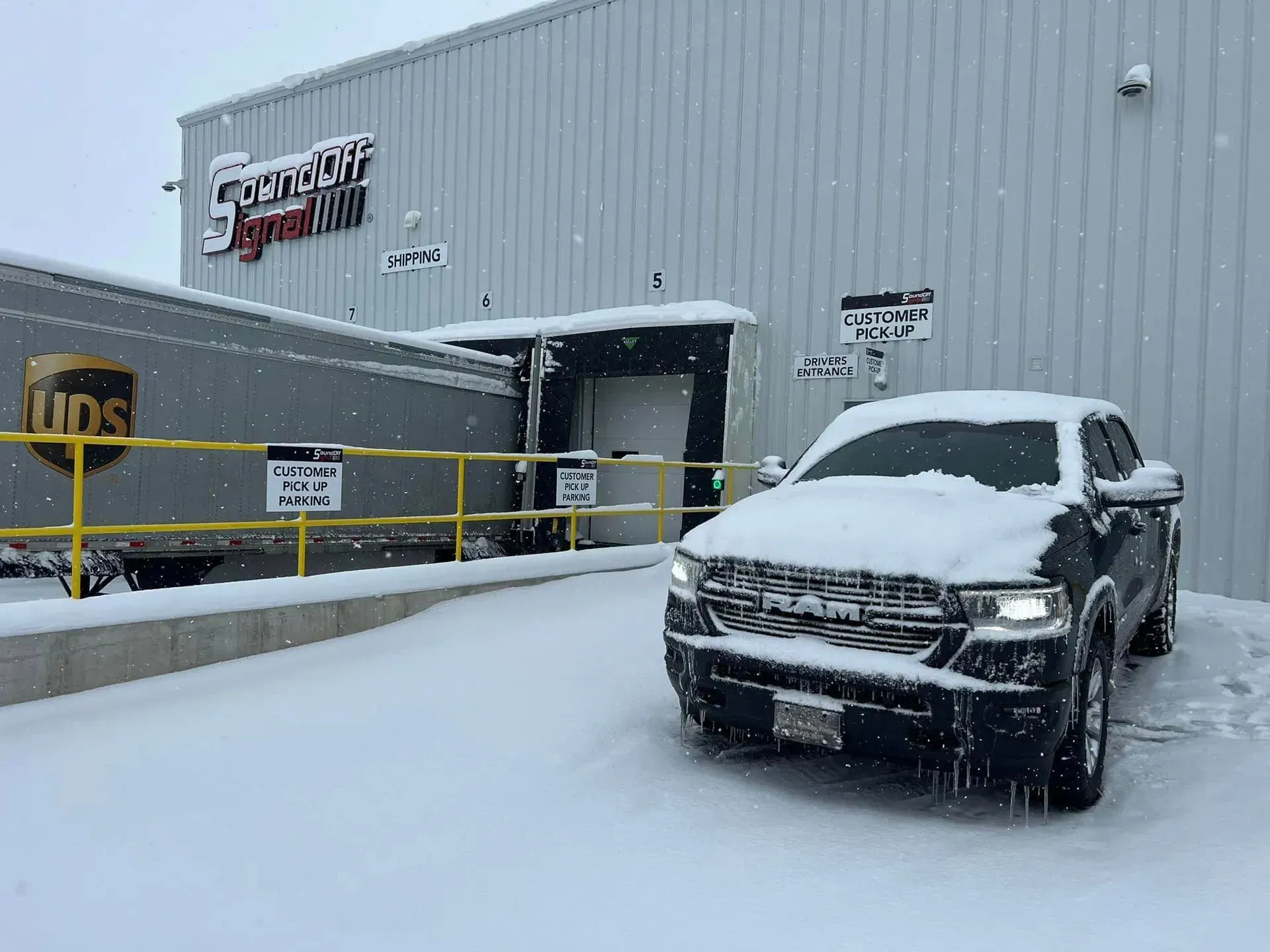 A truck is parked in front of a building in the snow.