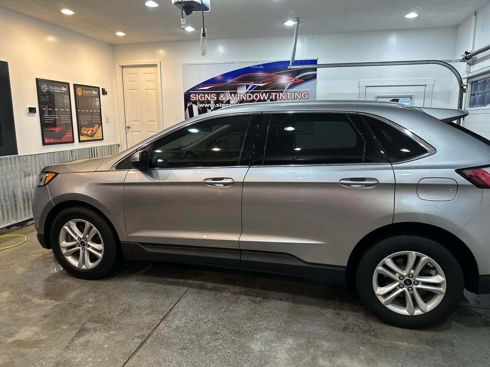 A silver ford edge is parked in a garage.