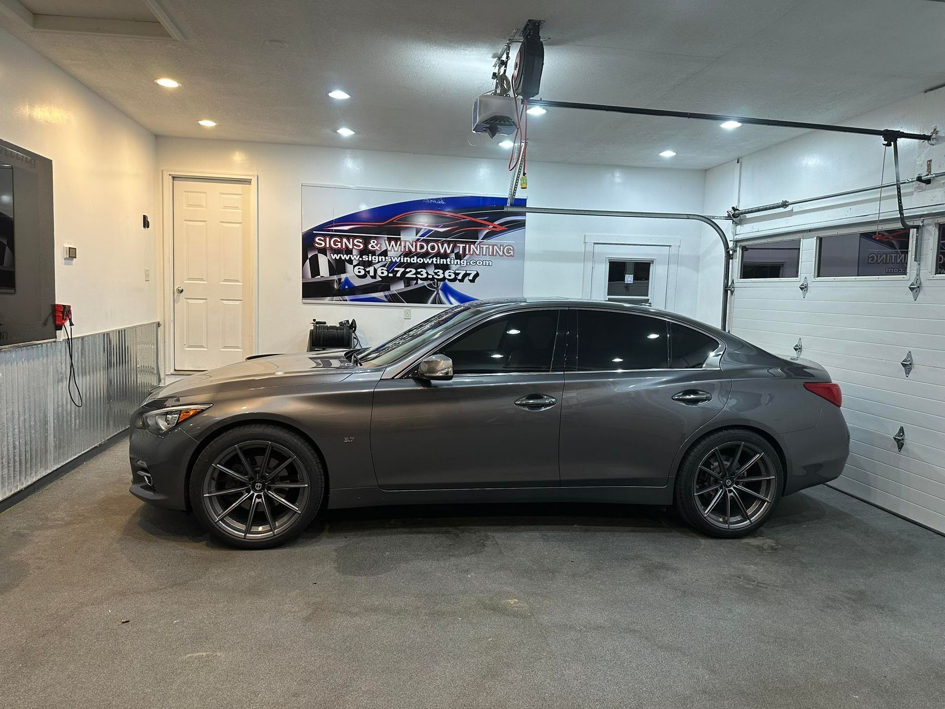 A gray car is parked in a garage next to a garage door.