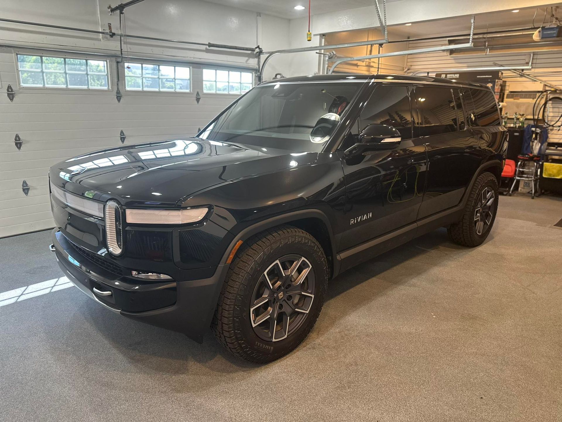 A black suv is parked in a garage next to a garage door.