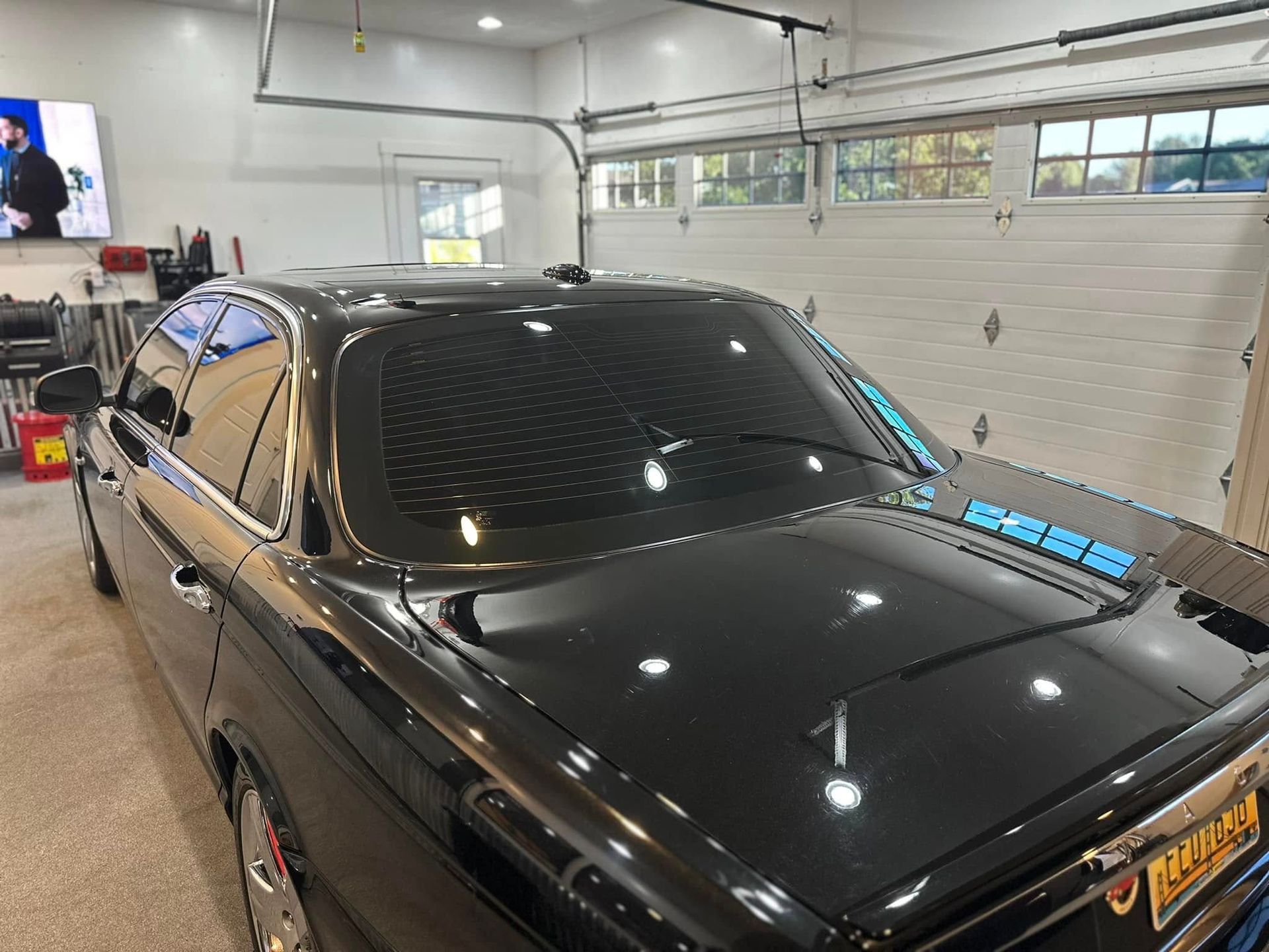 A black car is parked in a garage next to a white garage door.