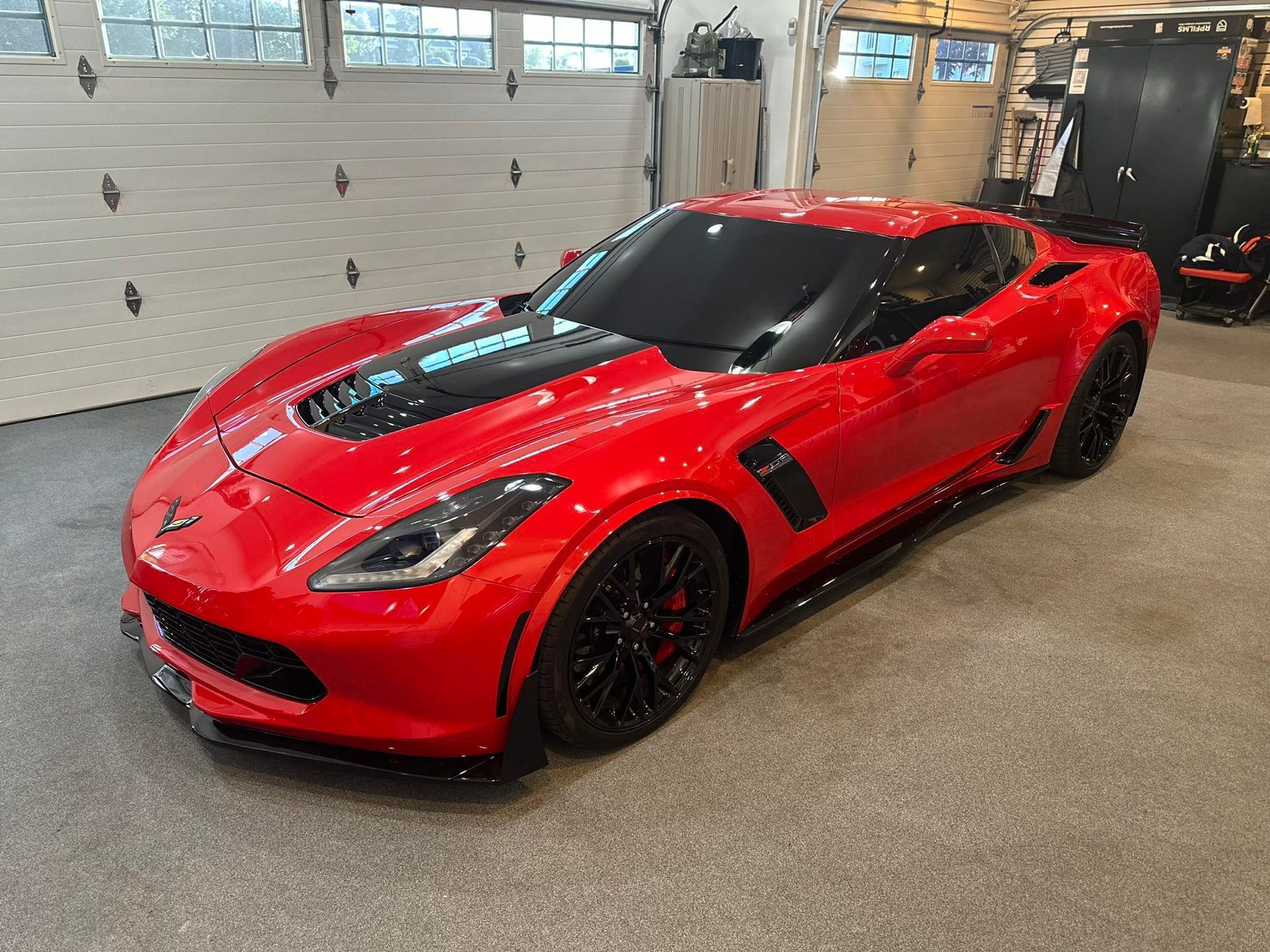 A red sports car is parked in a garage next to a garage door.