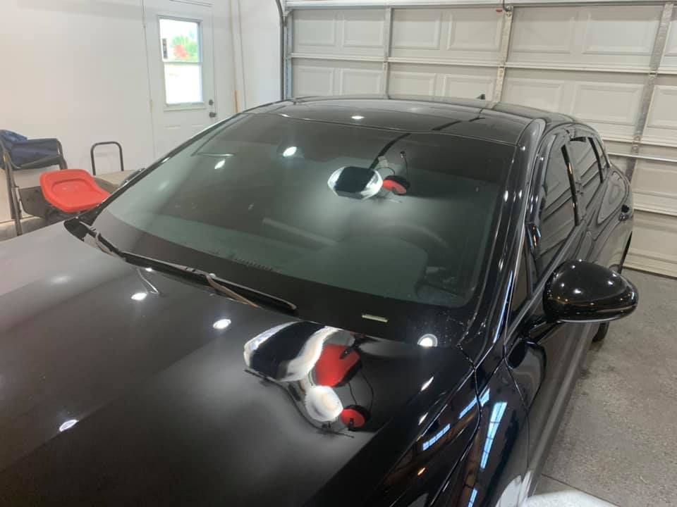 A black car is parked in a garage next to a garage door.