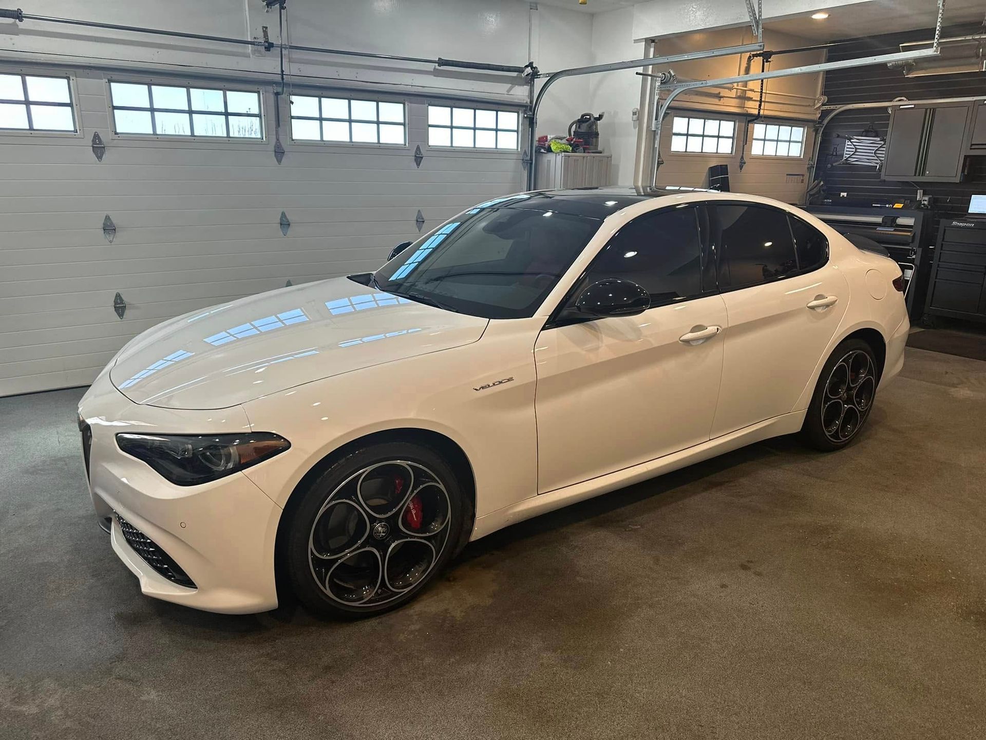 A white car is parked in a garage next to a garage door.