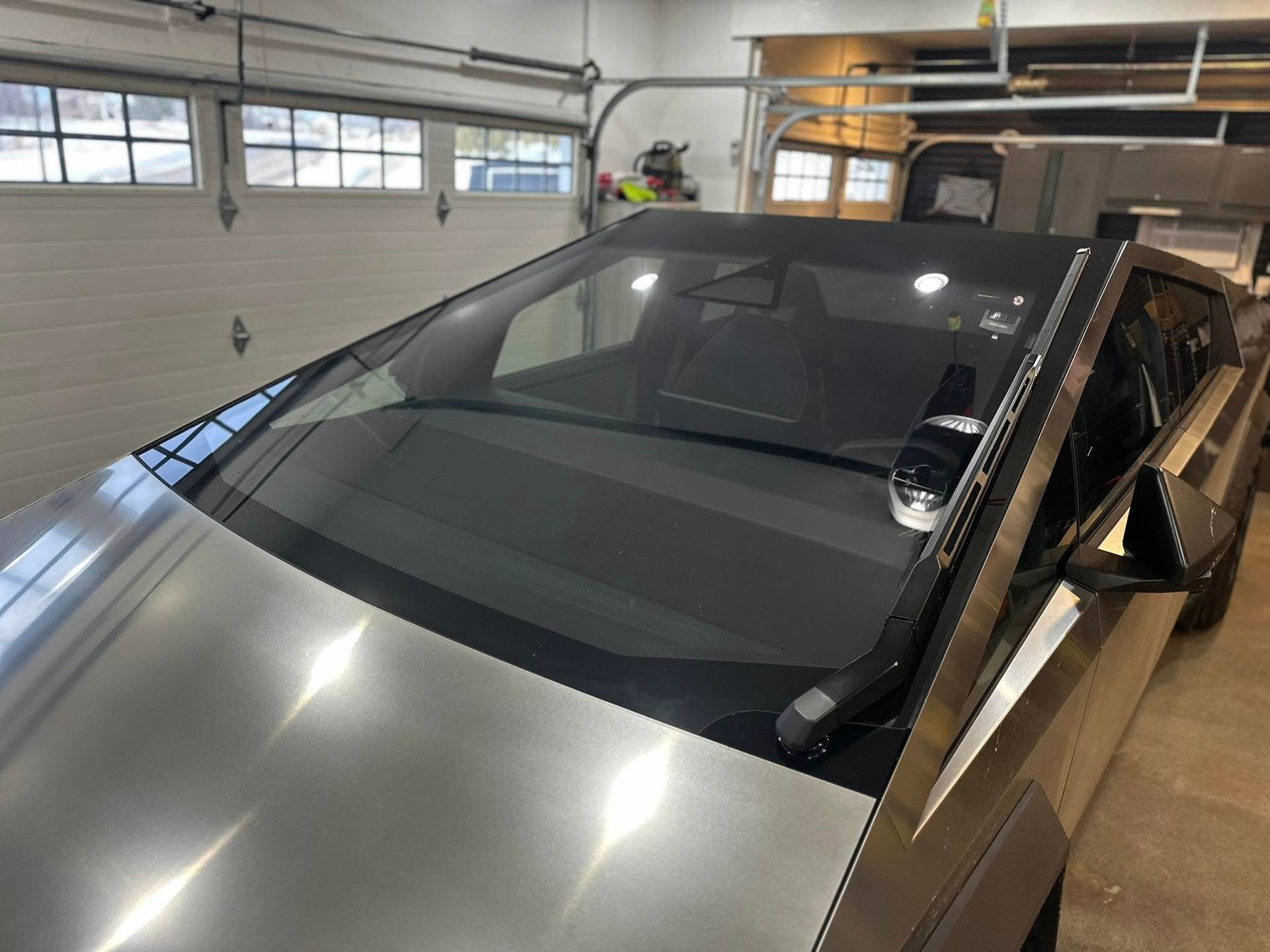 A silver tesla model s is parked in a garage.