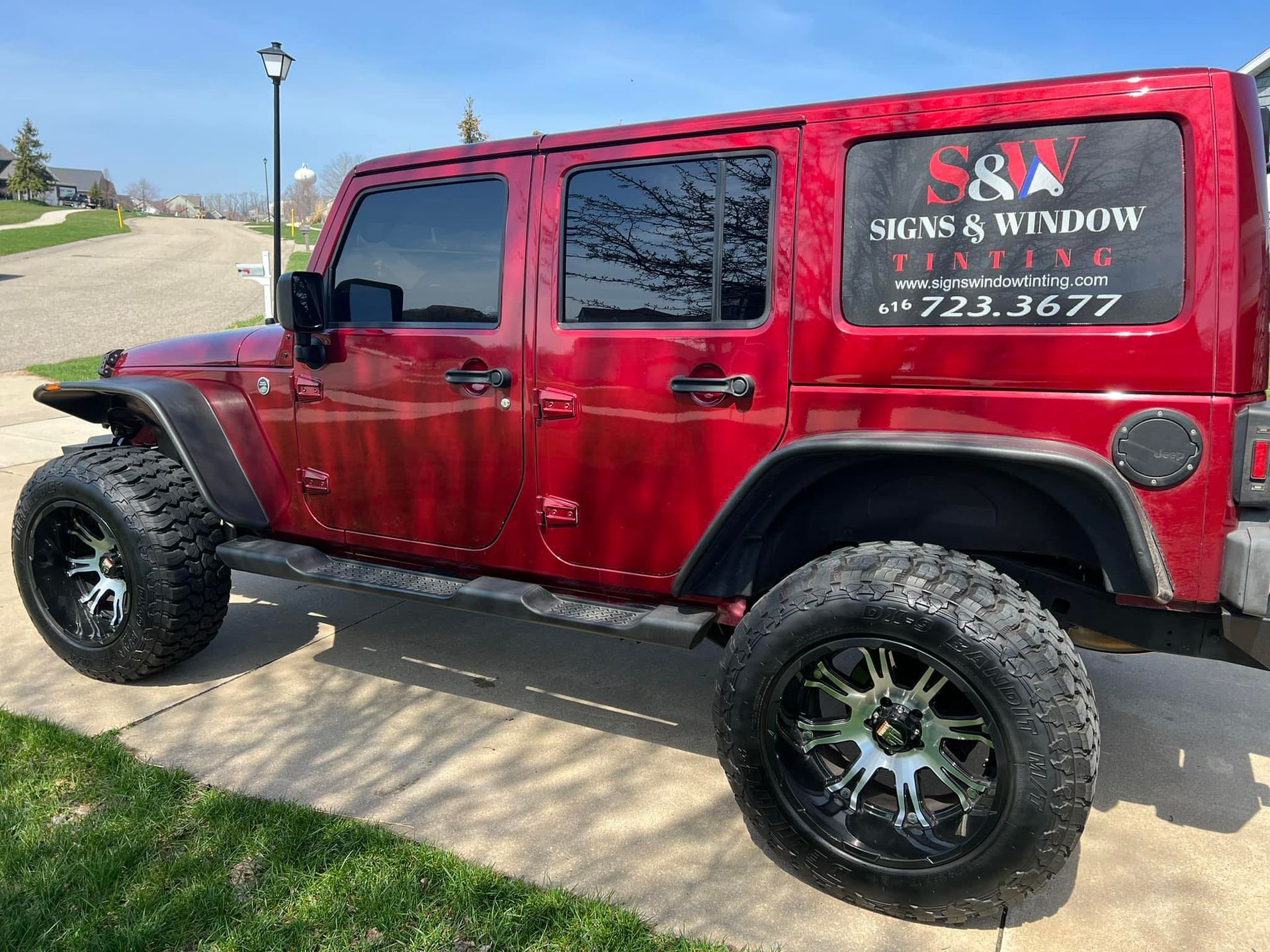 A red jeep is parked on the side of the road.