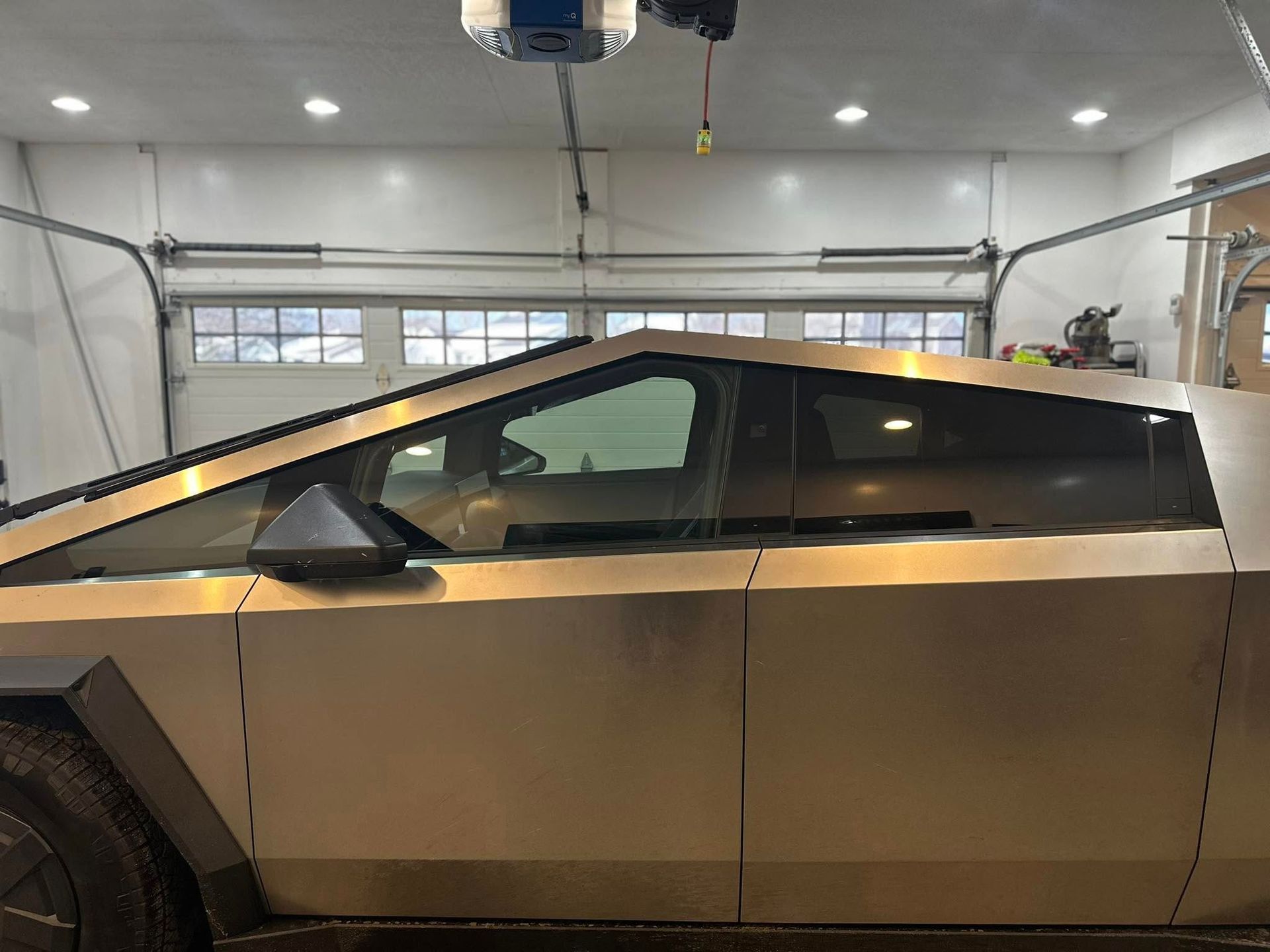 A tesla cybertruck is parked in a garage under a garage door.