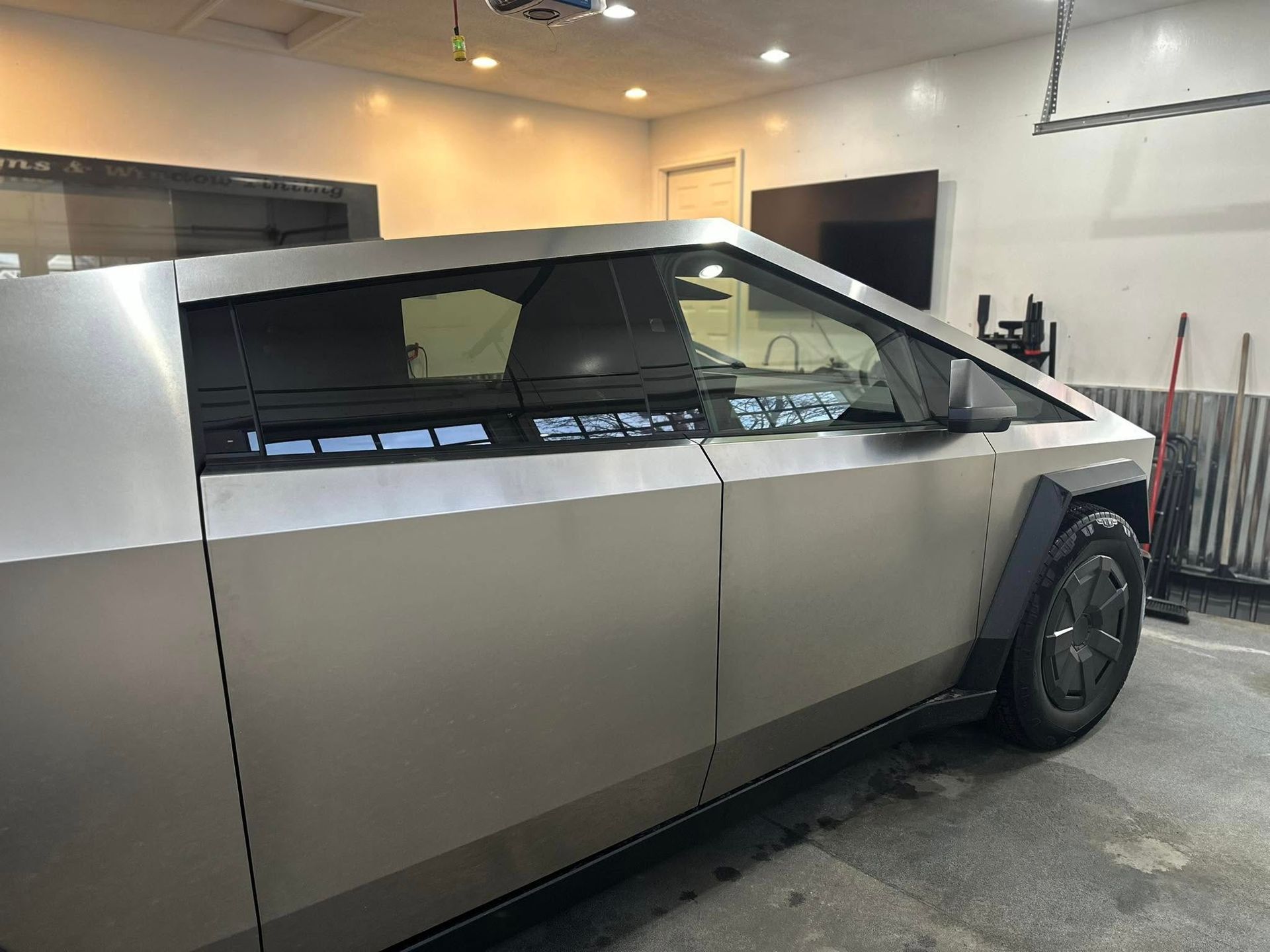 A silver tesla cybertruck is parked in a garage.
