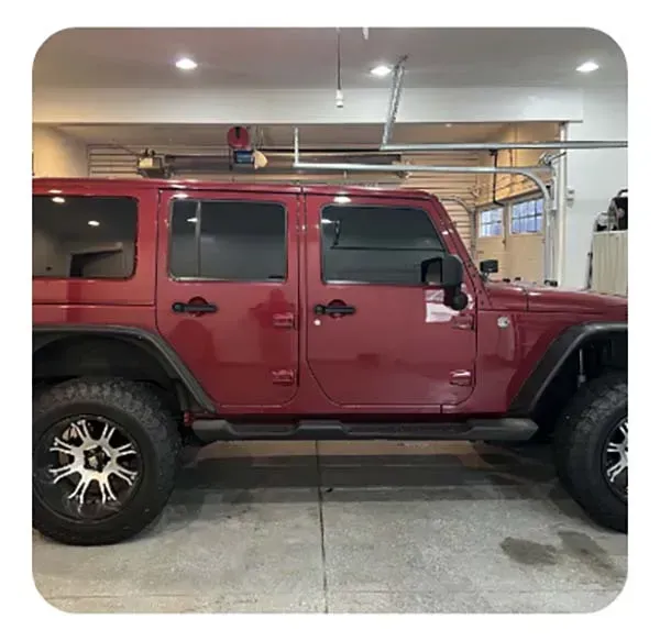 A red jeep is parked in a garage