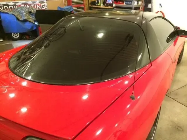 A red car with a black roof is parked in a garage