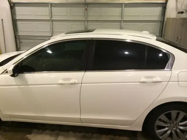 A white car is parked in front of a garage door.