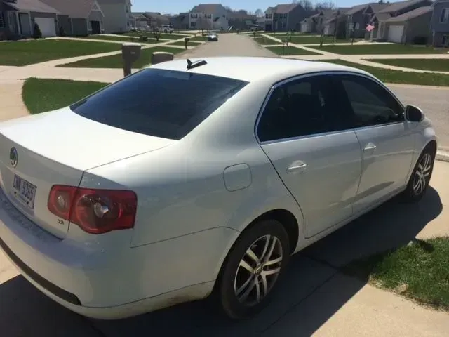 A white car is parked in a driveway in a residential neighborhood.