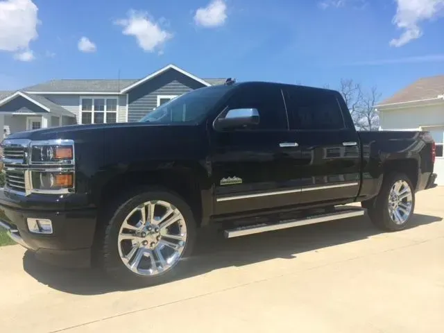 A black truck is parked in a driveway in front of a house.