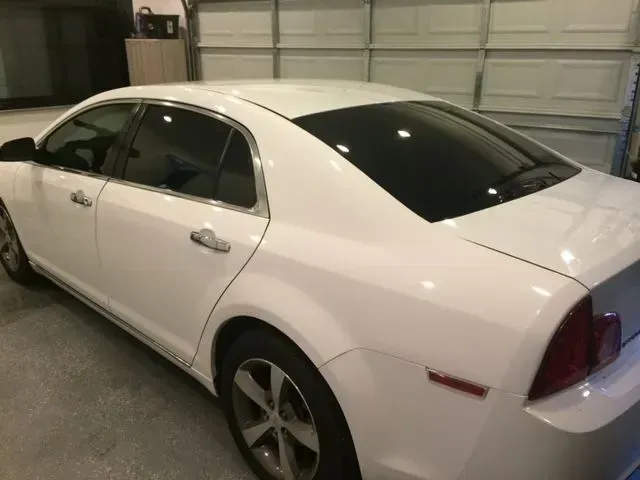 A white car is parked in a garage next to a garage door