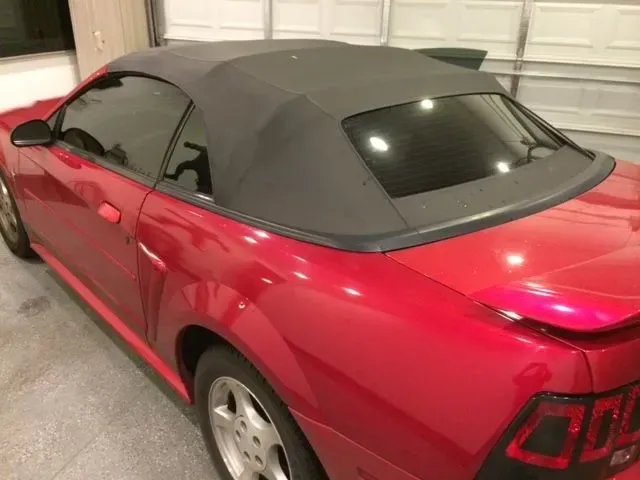 A red car with a black top is parked in a garage