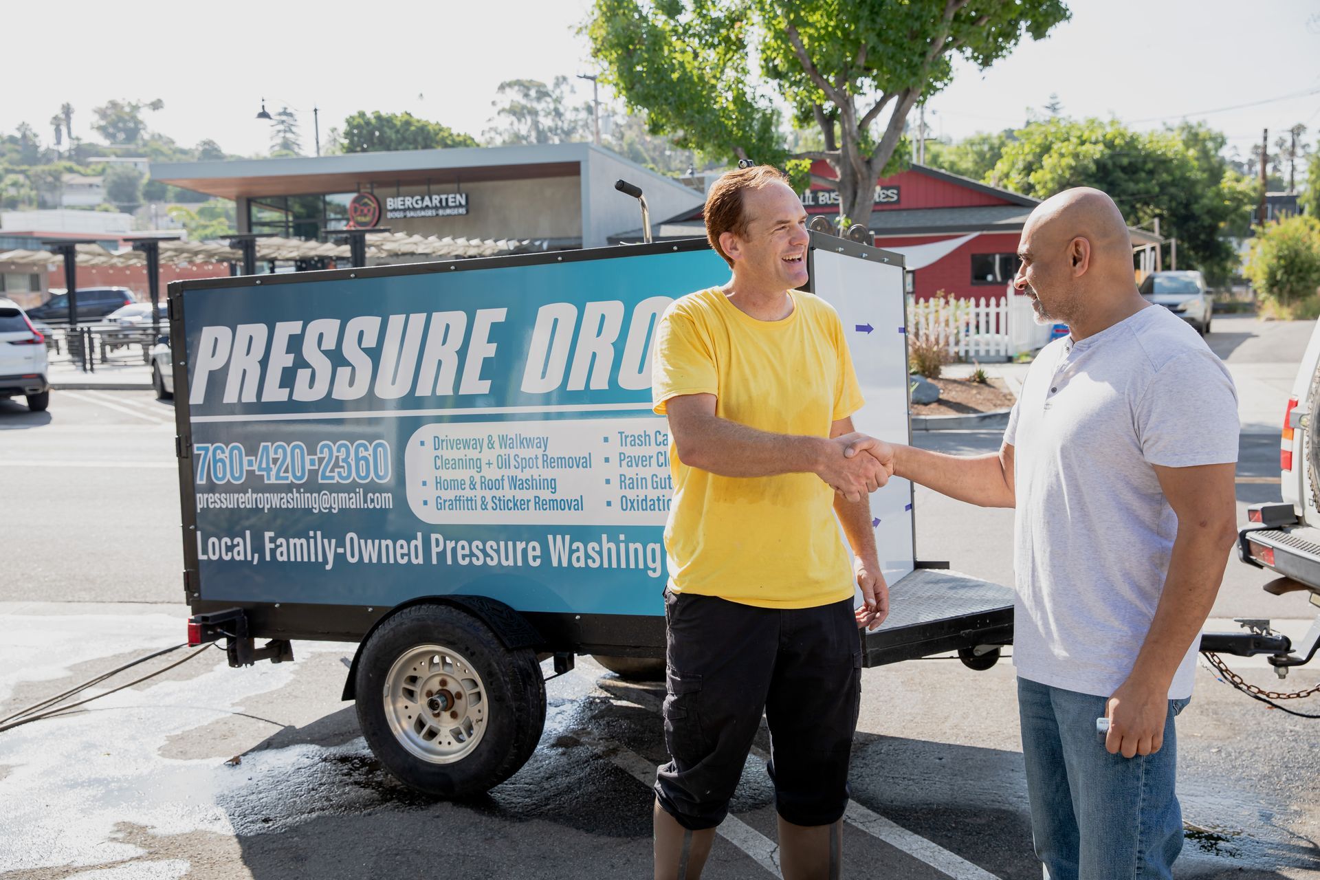 Two men shaking hands in front of a trailer that says pressure drain