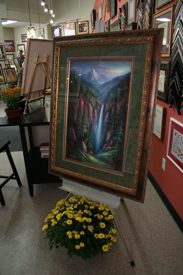 A painting of a waterfall is displayed on an easel