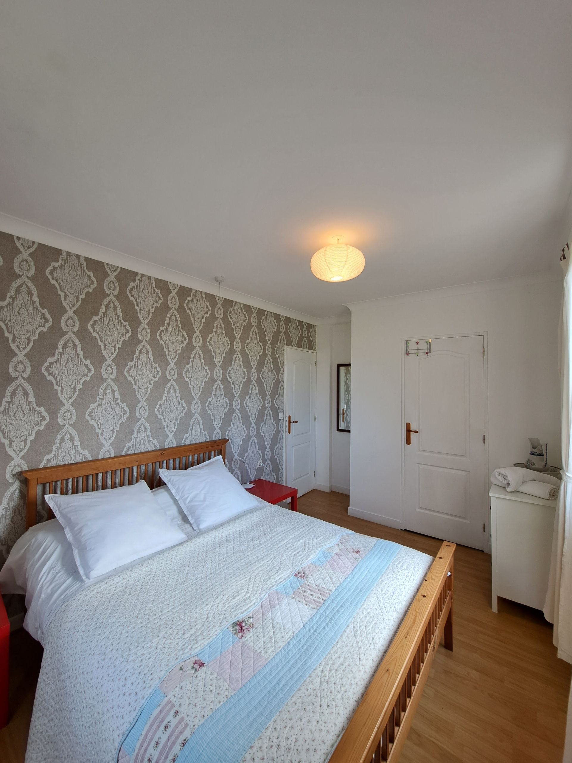 king sized bed with white bedlinen , grey and blue cushions and a blue runner
