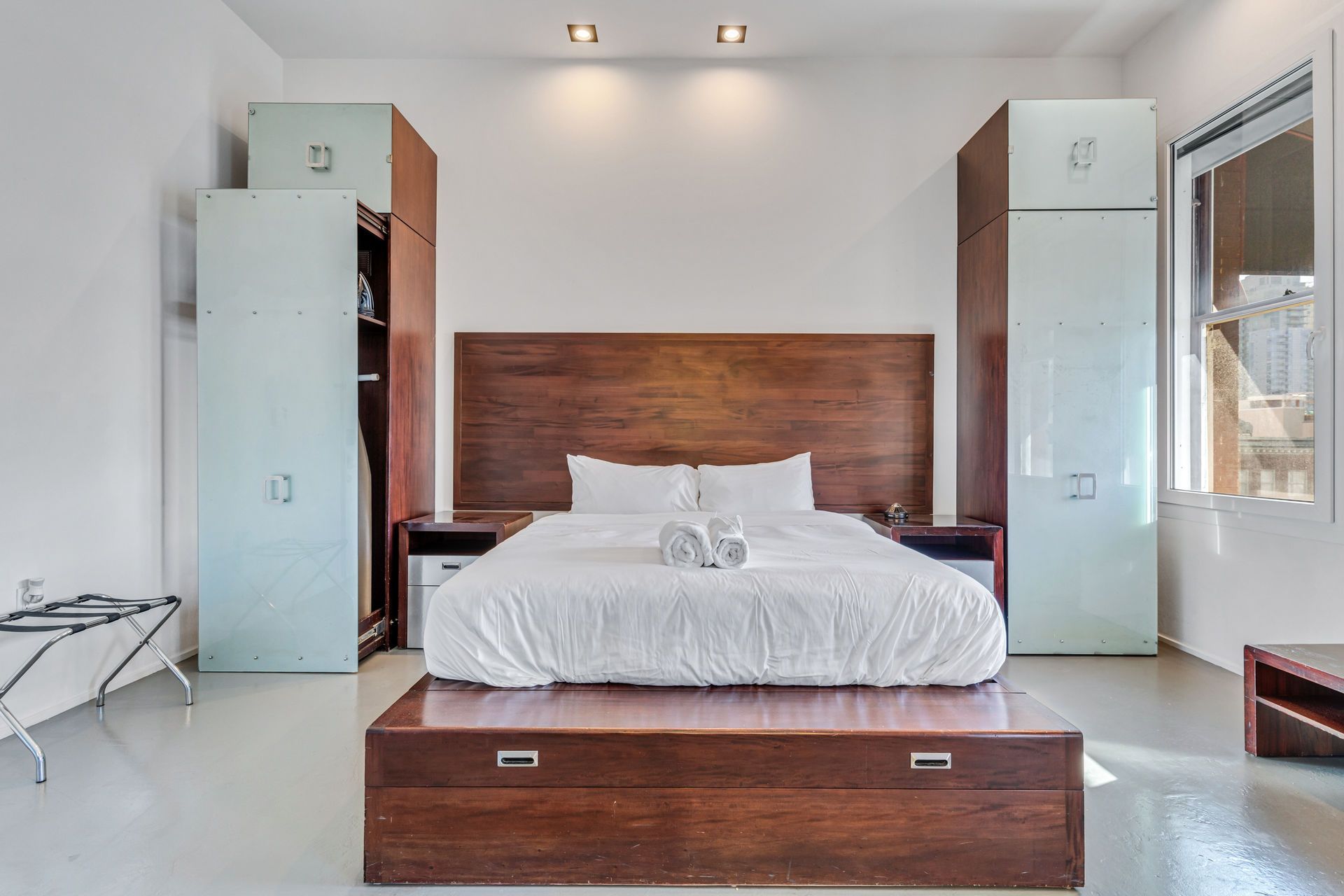 Bedroom with a large bed, wooden headboard, and two tall wardrobes on either side.