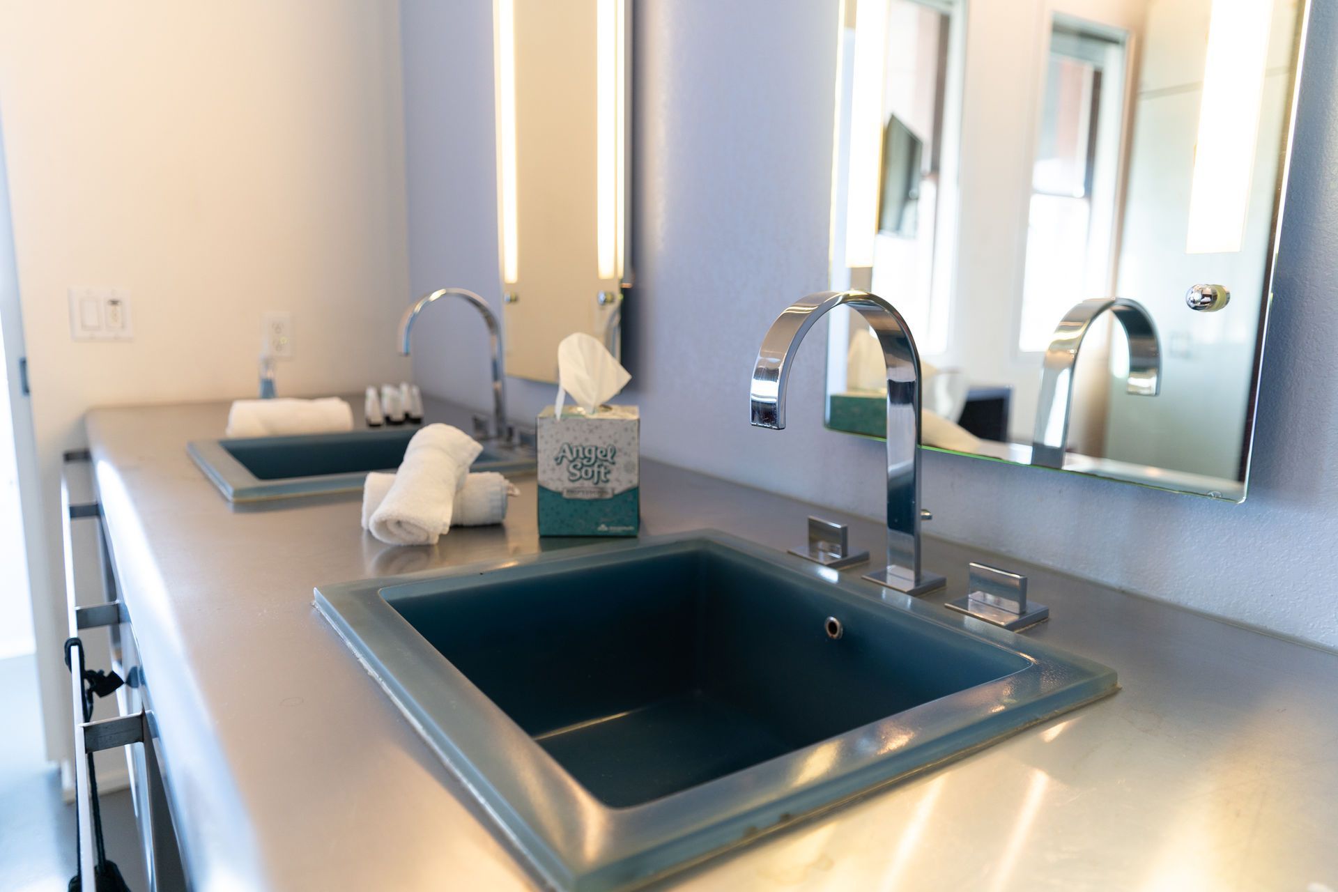 Bathroom with two teal sinks, chrome faucets, and a tissue box.