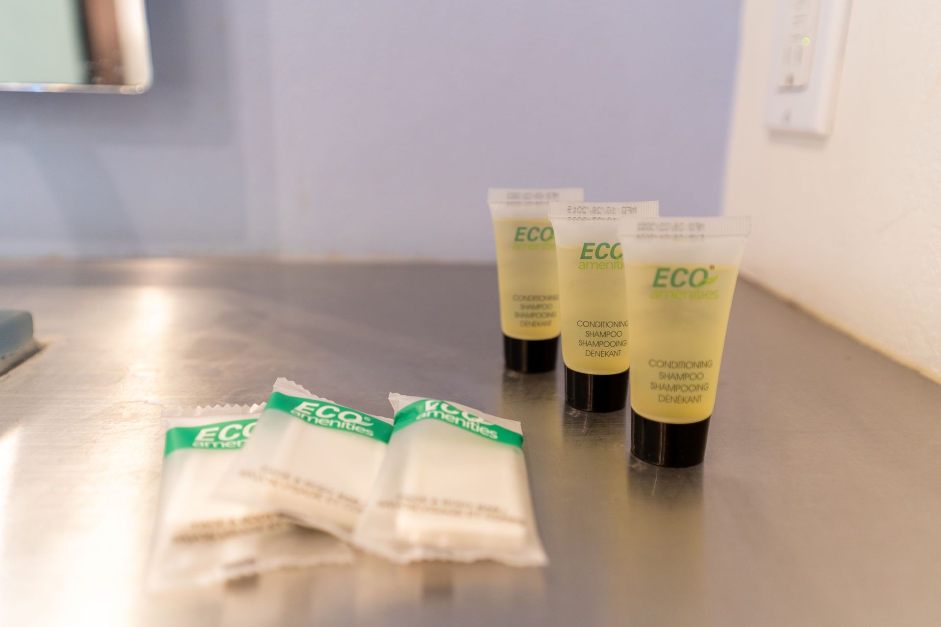 Toiletries: shampoo tubes and wrapped soaps on a metal surface.