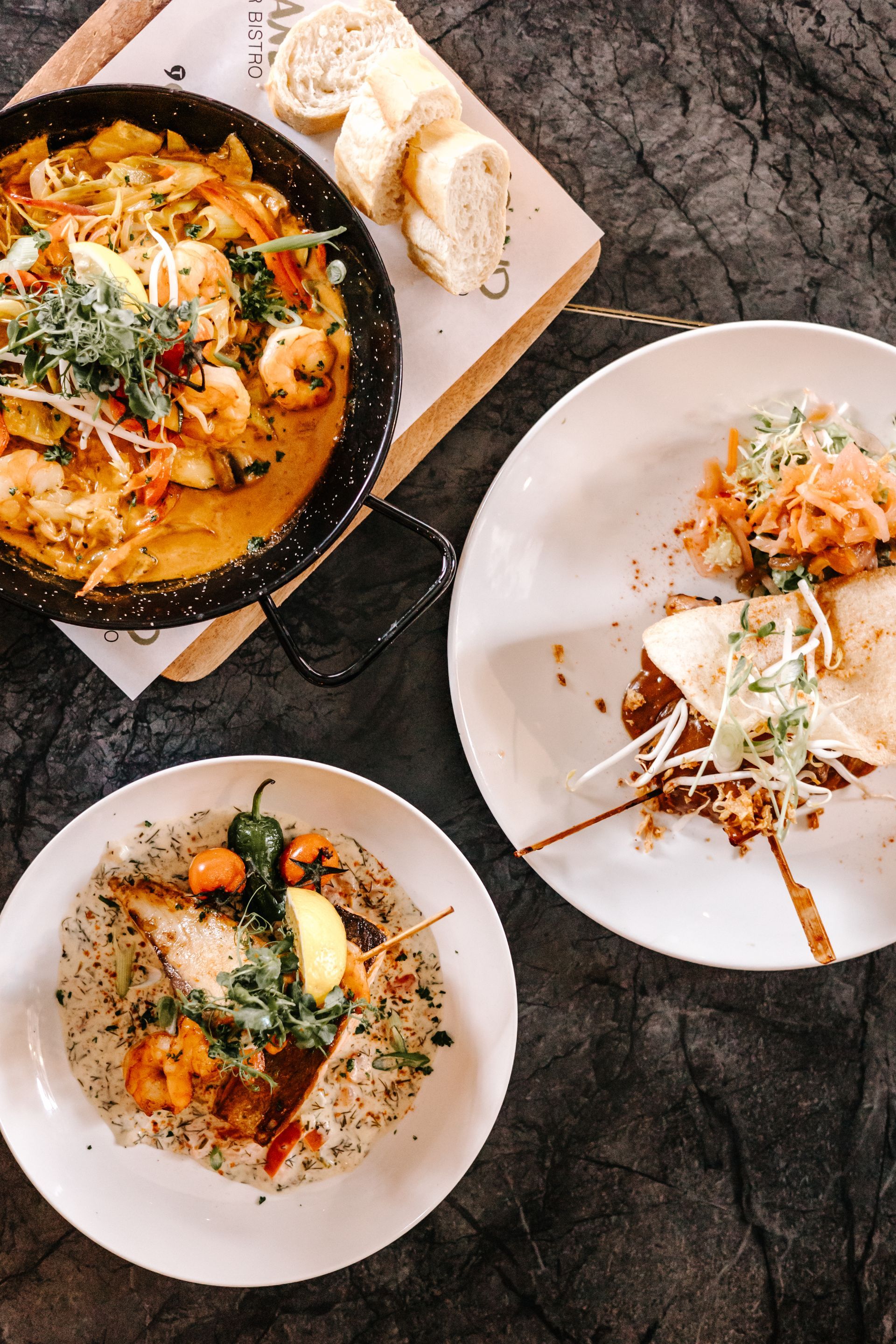 Er staan drie borden met eten op tafel, naast een pan met eten.