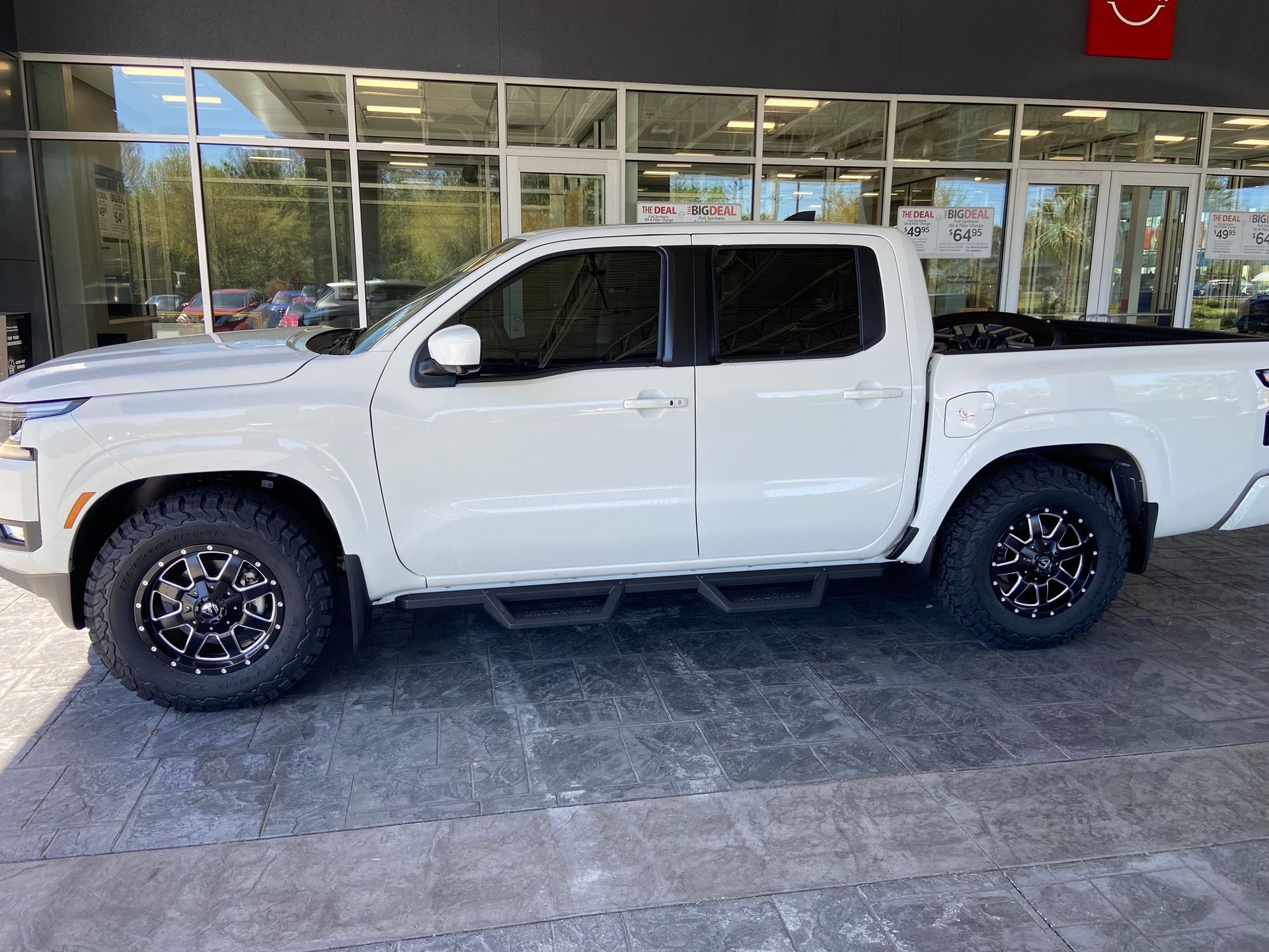 White pickup truck with black wheels parked in front of a building.