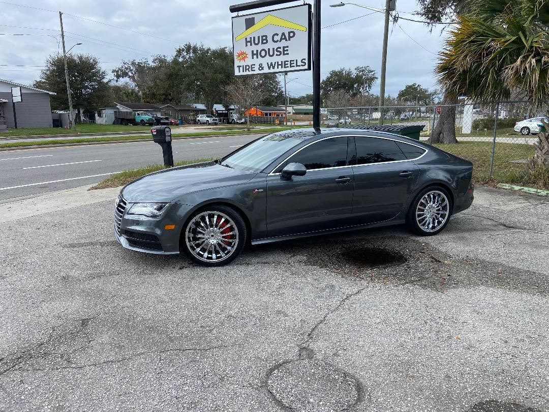 Grey Audi sedan with tinted windows parked by a Hub Cap House sign.