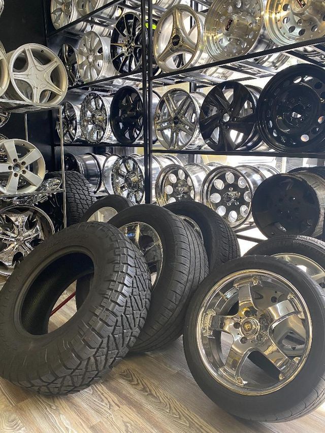 Shelves of car rims in a shop; tires and one rim are in the foreground.