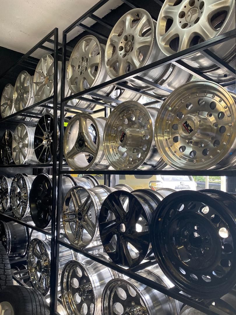 Racks displaying numerous shiny car wheels in various designs, likely at an auto parts store.