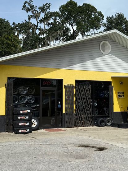 Tires and rims on display in a shop; a shelf with various rims in the background.
