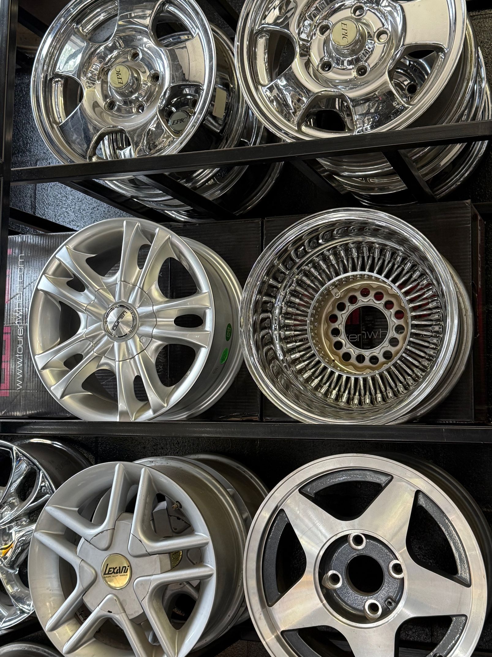 Silver car wheel with black tire on a concrete surface.